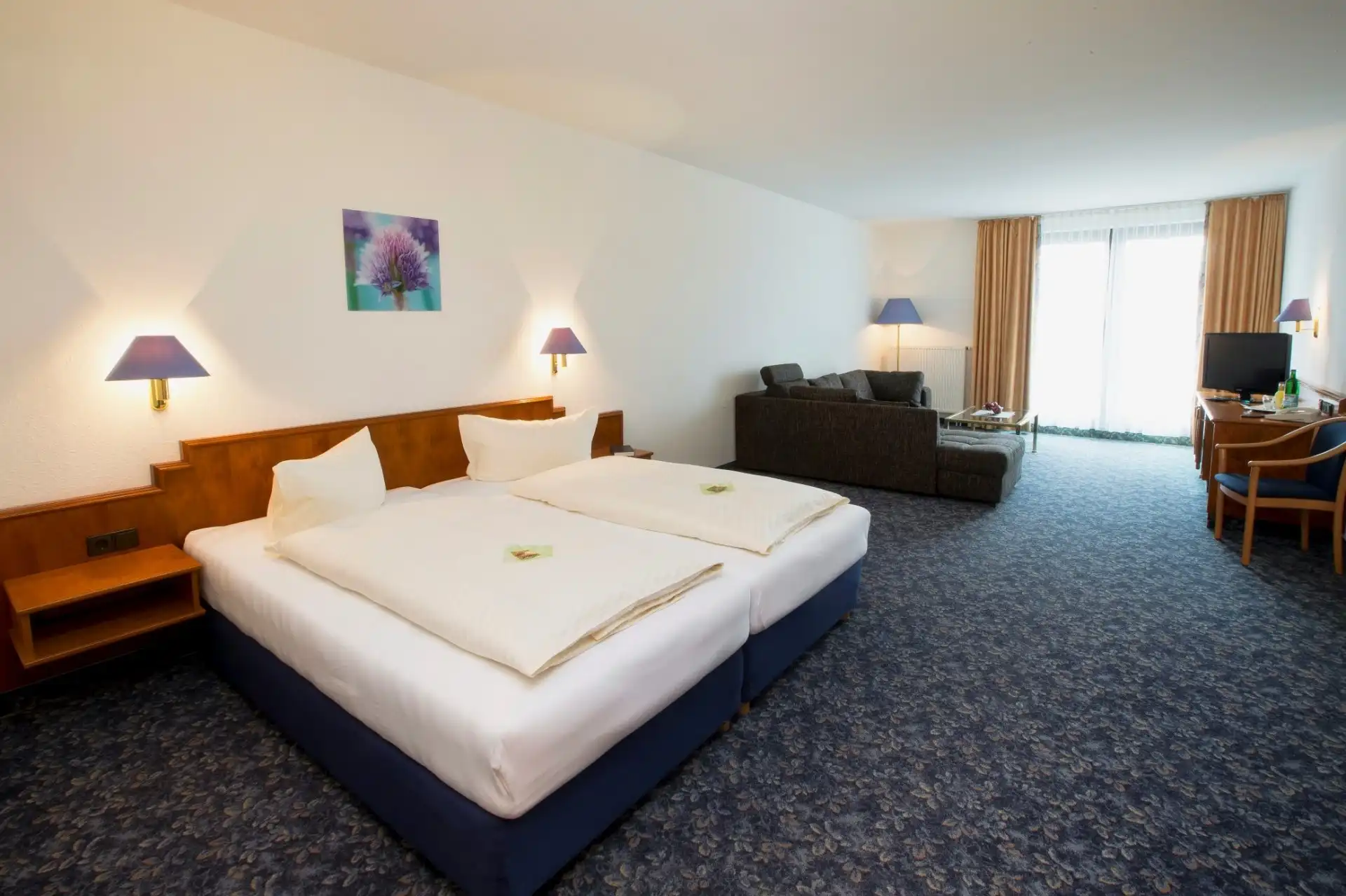 Ein Zimmer im Hotel Alpina Lodge in Oberwiesenthal mit zwei Einzelbettlaken und einem Wohnbereich mit Sofa und Fernseher