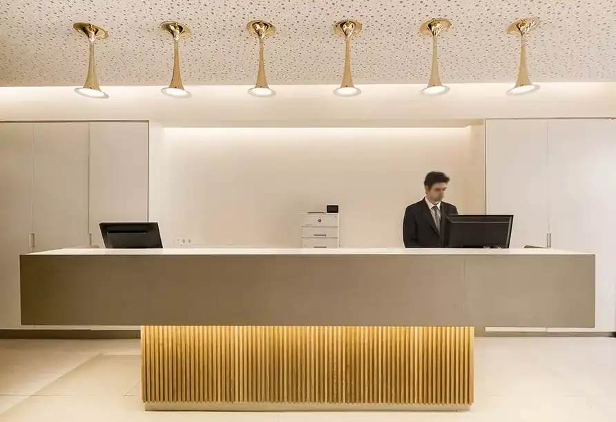 Ein luxuriöses Rezeptionsbereich eines Hotels mit moderner Design-Ausstattung. Ein Mann in einem schwarzen Anzug und einem