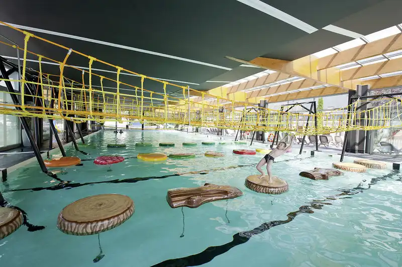 Einen Indoor-Aquapark im Hotel Sandra & Spa im Ostseebad Pogorzelica. Ein Mensch springt auf einem Sprungbrett in das