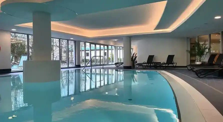 Ein Indoorpool im Dorint Hotel Sanssouci in Potsdam. Das Wasser ist ein klares blau, und die Umgebung ist gut beleuchtet mit