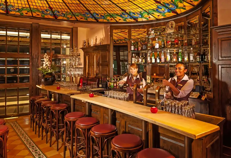 Ein Bar im Dorint Hotel Sanssouci in Potsdam mit einem Holzboden und einem gläsernen Deckenfenster. Die Bar ist mit