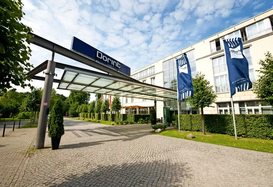 Das Dorint Hotel Sanssouci in Potsdam. Ein großes Hotelgebäude mit einem großen Eingangsschutz ist sichtbar. Auf dem Schutz