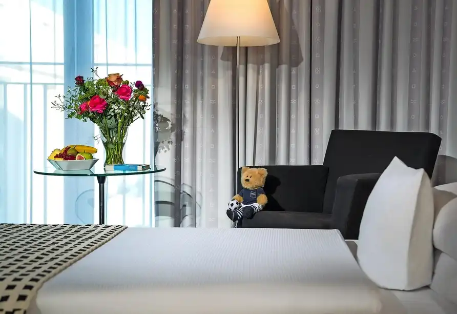 Ein Zimmer im Dorint Hotel Sanssouci in Potsdam mit Blick auf ein helles Fenster, auf dem ein Tisch mit einem Vasen mit