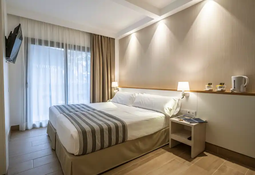 Ein modernes Hotelzimmer mit einem Bett, einem Nachttisch und einem Balkon. Der Raum ist gut beleuchtet und bietet einen
