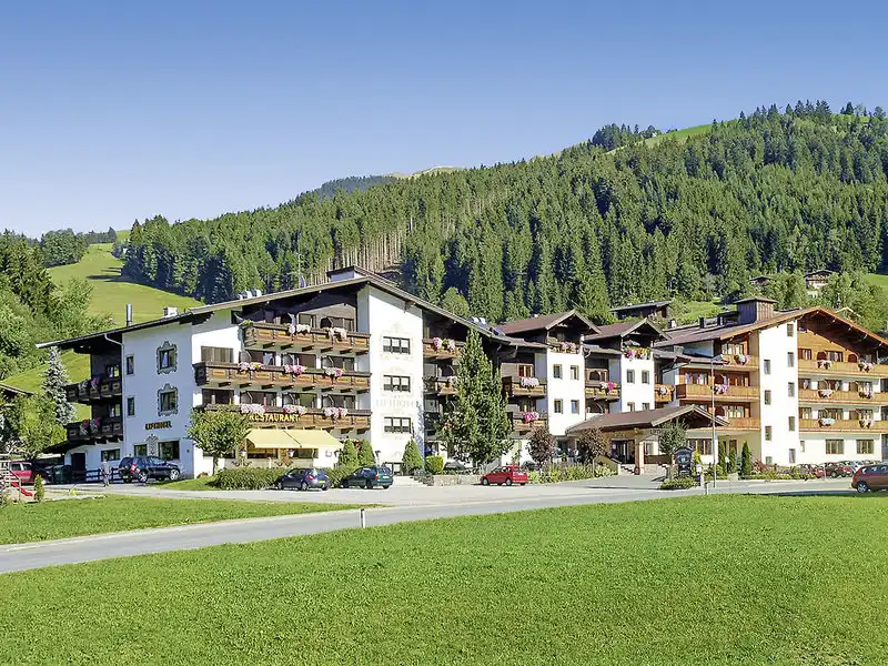 Ein großes, mehrstöckiges Hotel mit vielen Balkonen, die sich auf einem Hügel mit dichtem Grünlager befindet. Das Hotel ist