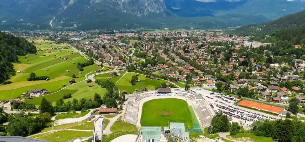 Einen üppigen Landschaftsbild mit einem Blick auf eine Stadt und Bergen im Hintergrund. Im Vordergrund befindet sich ein