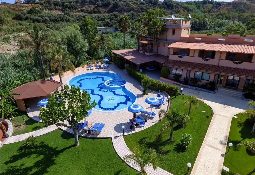 Einen Außenpool des Hotels in Kalabrien. Der blaugelbe Pool ist mit blauen Lounges umgeben und wird von grünen Rasenflächen