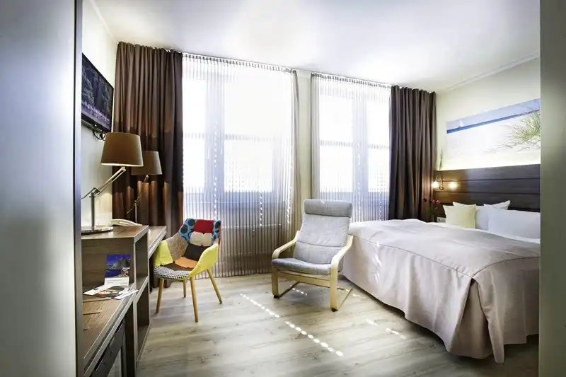 Ein modernes Hotelzimmer mit Blick auf die Kieler Förde. Das Zimmer ist gut beleuchtet und mit einem Bett, einem
