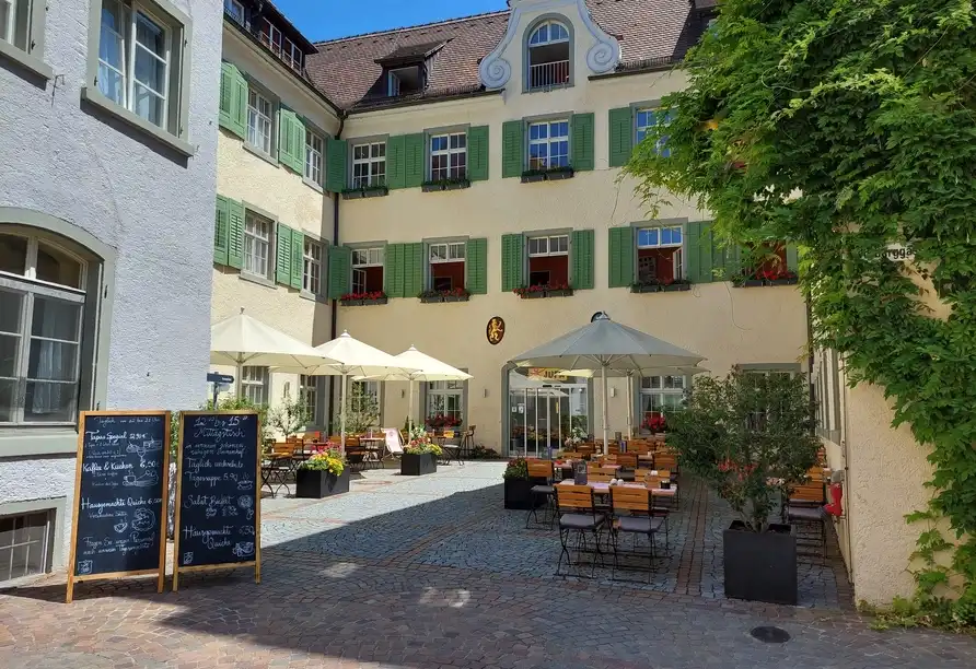 Ein charmantes Café oder Restaurantbereich im JUFA Hotel Meersburg am Bodensee. Die Außenanordnung umfasst mehrere Tische