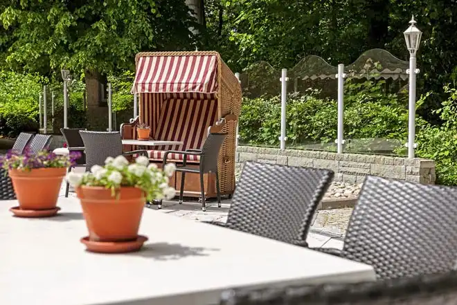 Einen Außenbereich des Upstalsboom Landhotels in Varel, Friesland. Auf einem Tisch sind zwei Keramikbecher mit Blumenstücken