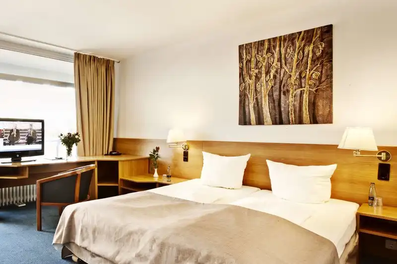 Ein Zimmer im Hotel Plöner See by Tulip mit einem Bett, einem Schreibtisch mit Stuhl und einem Fernseher. Die