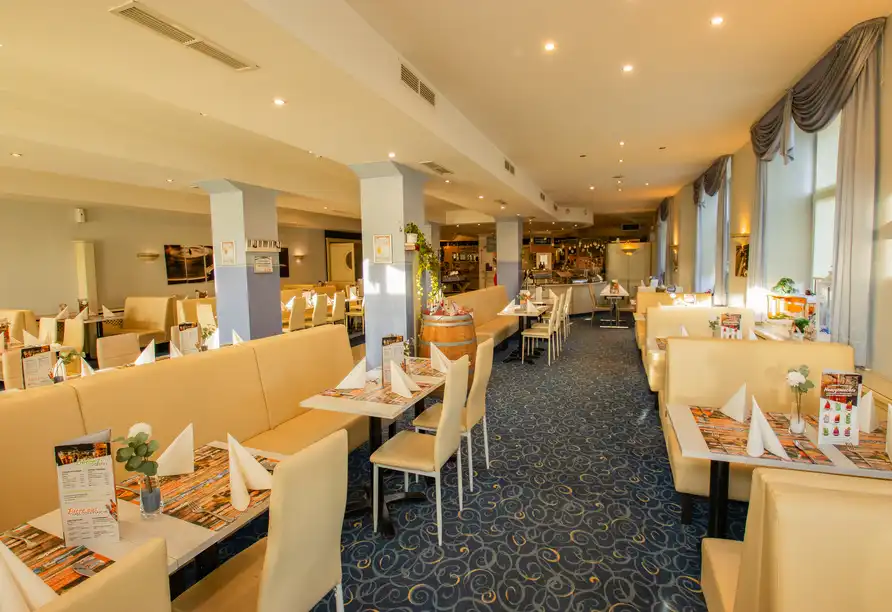 Ein elegantes Restaurant mit weißem und gelbem Möbel, blauen Teppichen und hellen Lichtern. Die Atmosphäre ist einladend und