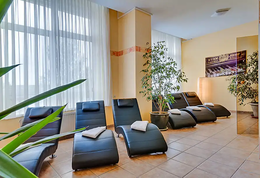 Ein Loungebereich im Hotel Porzellanstadt Meißen. Es gibt mehrere schwarze Ledersessel mit weißen Handtüchern auf den