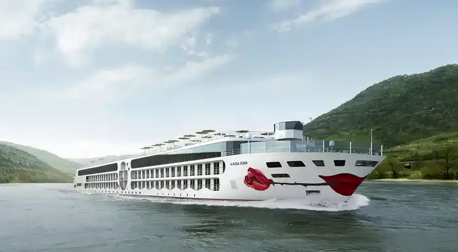 Ein großes Flusskreuzfahrtschiff, das A-ROSA SENA genannt wird. Das Schiff ist weiß mit roten Dekorationen, darunter einem