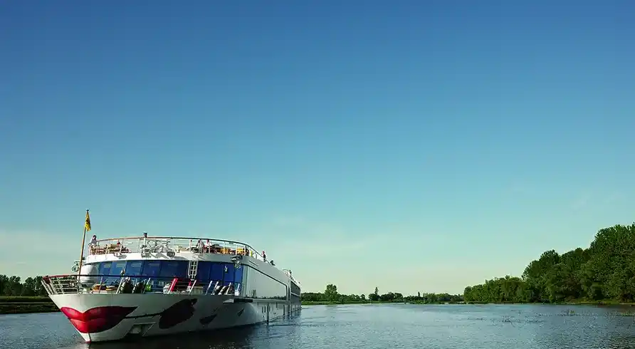Ein großes Boot, das auf dem Fluss Rhein fährt. Das Boot ist weiß mit roten Details und hat einen Deckenbereich mit vielen