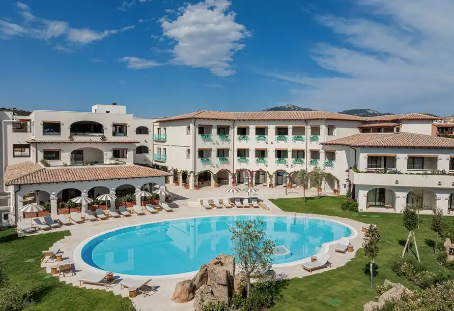 Ein luxuriöses Hotel mit einem großen Außenpool und umfassender Grünfläche bietet eine ideale Umgebung für eine entspannende