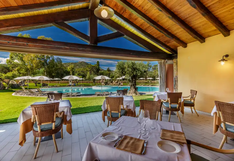 Ein luxuriöses Restaurant mit Blick auf einen Outdoor-Pool und umfassende Außenbereiche. Die Dekoration ist einladend, mit
