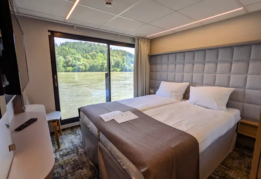 Ein Zimmer mit Blick auf den Donaufluss. Das Zimmer verfügt über zwei Betten mit weißen Bettwäsche und einem