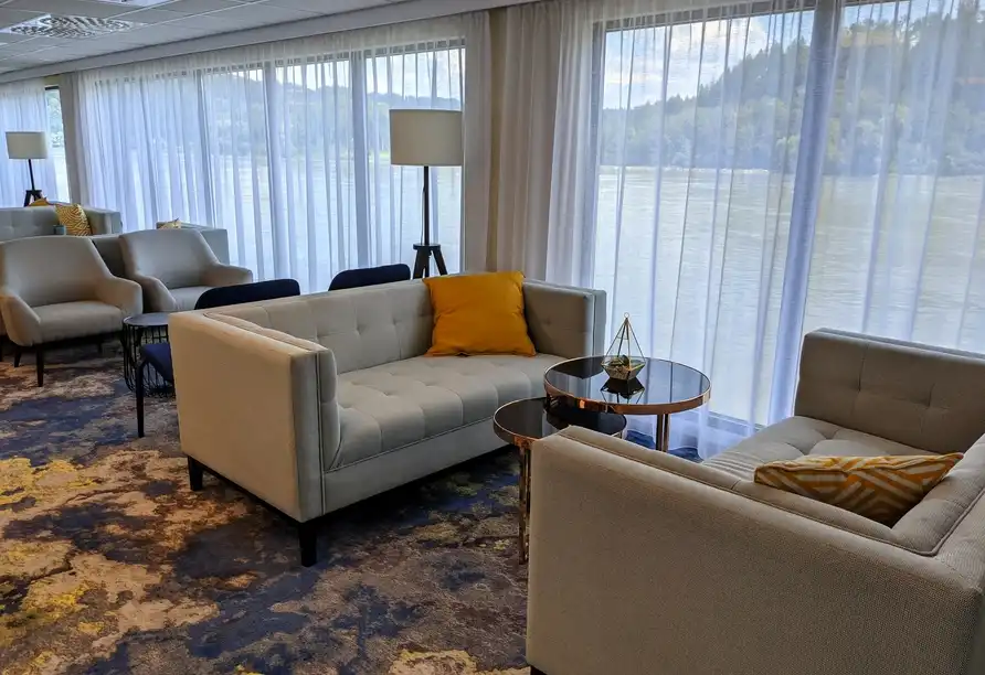 Ein Wohnzimmer im Hotel Reitenberger in Marienbad mit weißen Sofas, einem goldenen Kissen und einem Tisch mit einem Dekor