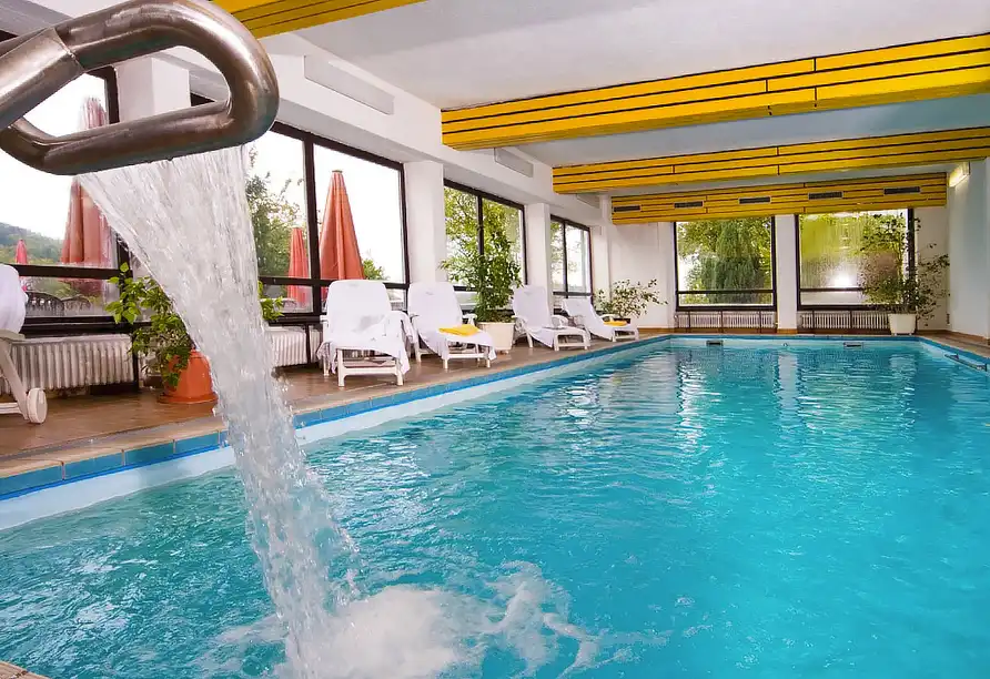 Beheiztes Hallenbad mit Wasserfall und Liegestühlen im Wellnessbereich des Hotels