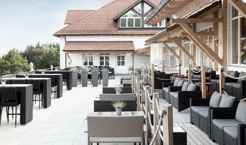 Einen Außenbereich eines Hotels mit verschiedenen Möbeln und Dekorationen. Es handelt sich um den Burghotel am hohen Bogen