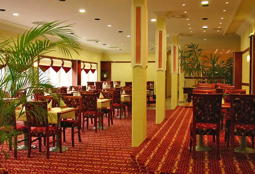 Ein Restaurant im Hotel zur Riede in Delmenhorst mit roten und gelben Dekorationen und Pflanzen