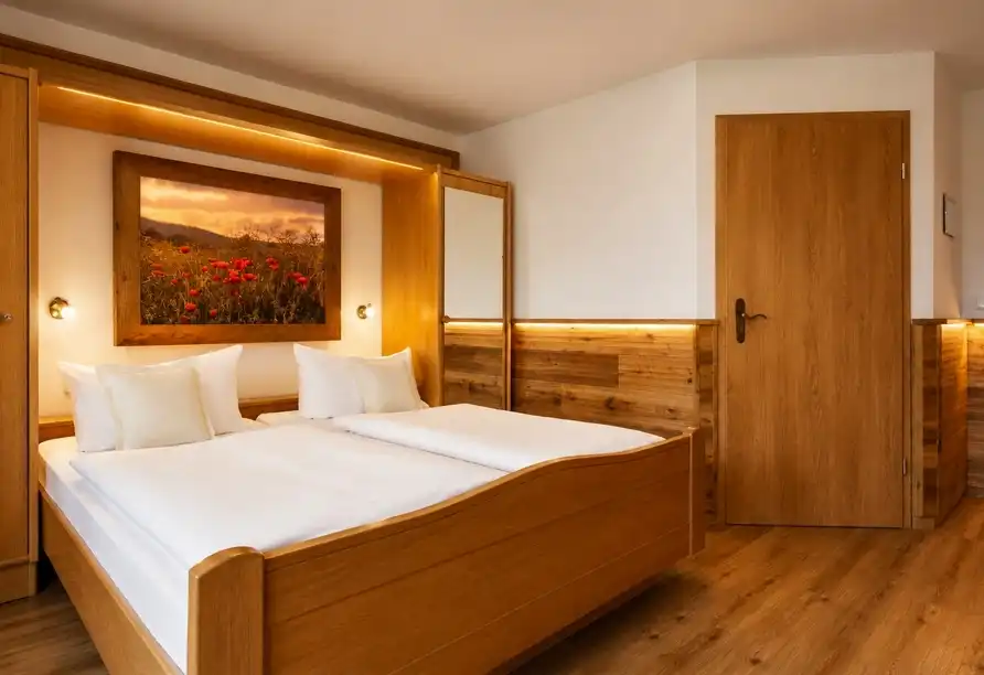 Ein Schlafzimmer im Hotel Sauerländer Hof in Willingen mit einem Holzbett, weißer Bettwäsche und einem Bild von roten Blumen