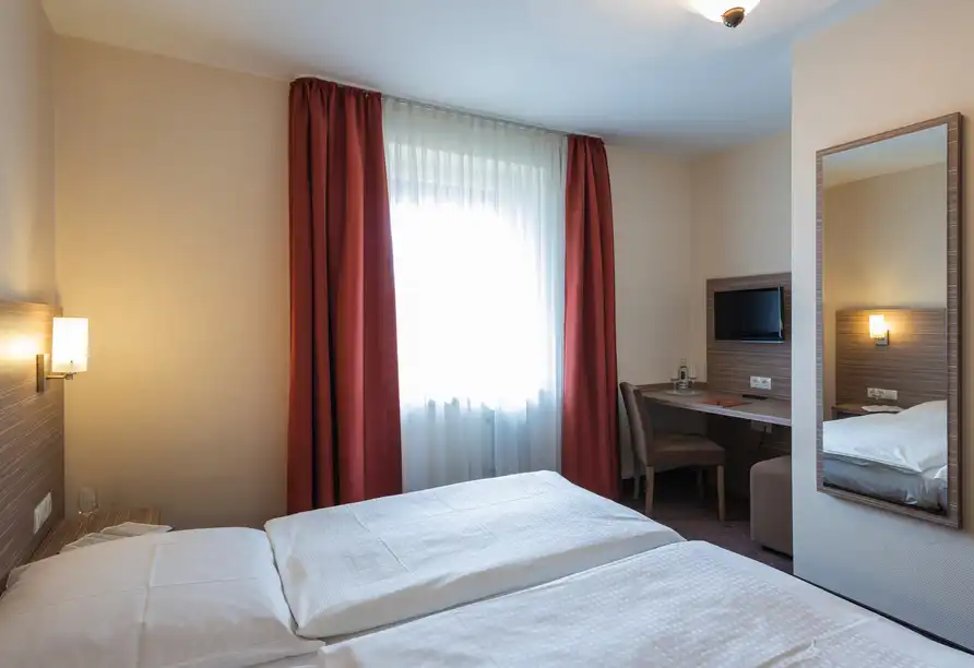 Ein Zimmer im Hotel Eisbach in Ransbach-Baumbach. Das Zimmer ist mit einem doppelten Bett ausgestattet, das mit weißen