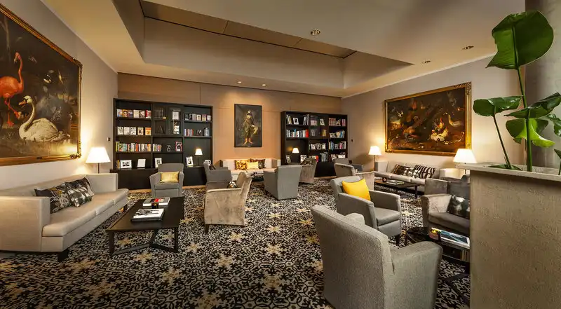 Ein luxuriöses Wohnzimmer mit einem orientalischen Ambiente, ein großes Bücherregal mit verschiedenen Büchern und Gemälden,