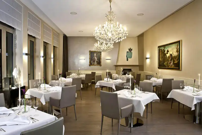 Ein luxuriöses Restaurant mit einer großen Hängelaterne, weiß gekleideten Tischen und Dekorationen, die einen einladenden