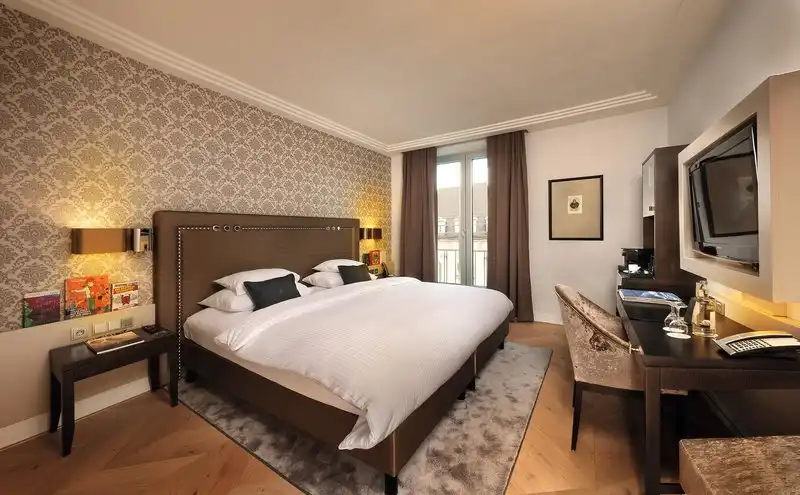Ein Schlafzimmer im Hotel Maximilian's in Augsburg mit einem großen Bett, einem Arbeitsbereich mit Schreibtisch und einem