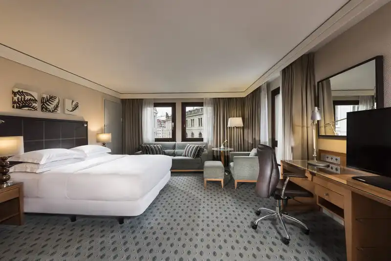 Ein luxuriöses Zimmer im Hotel Hilton Dresden. Das Zimmer verfügt über ein großes Bett mit weißem Bettlauf und einem