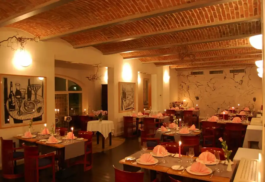 Ein Esszimmer im Hotel Vierseithof in Luckenwalde Brandenburg, decorated with warm lighting, rustic brick walls, and elegant