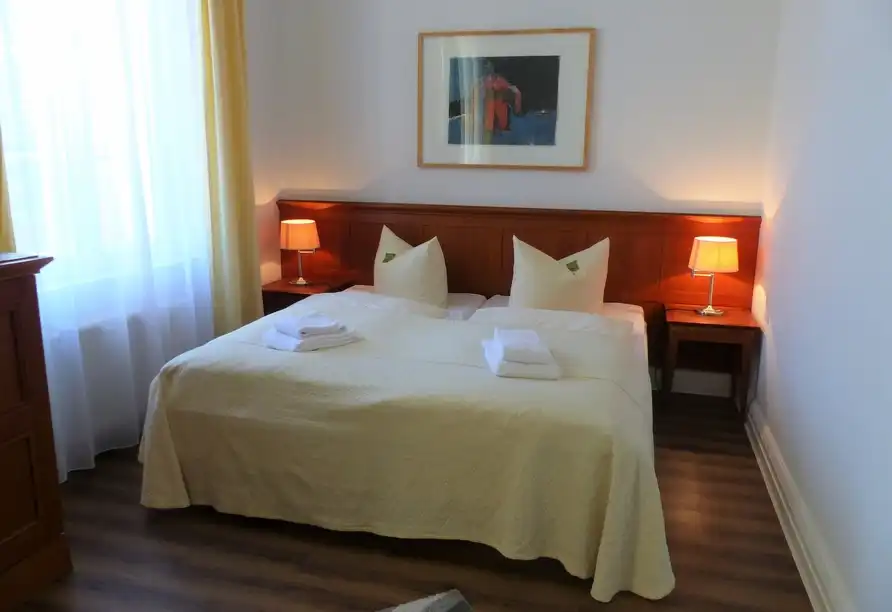 Ein Zimmer im Hotel Vierseithof in Luckenwalde mit einem doppelten Bett, einem Holzbrett an der Kopfseite und beiden