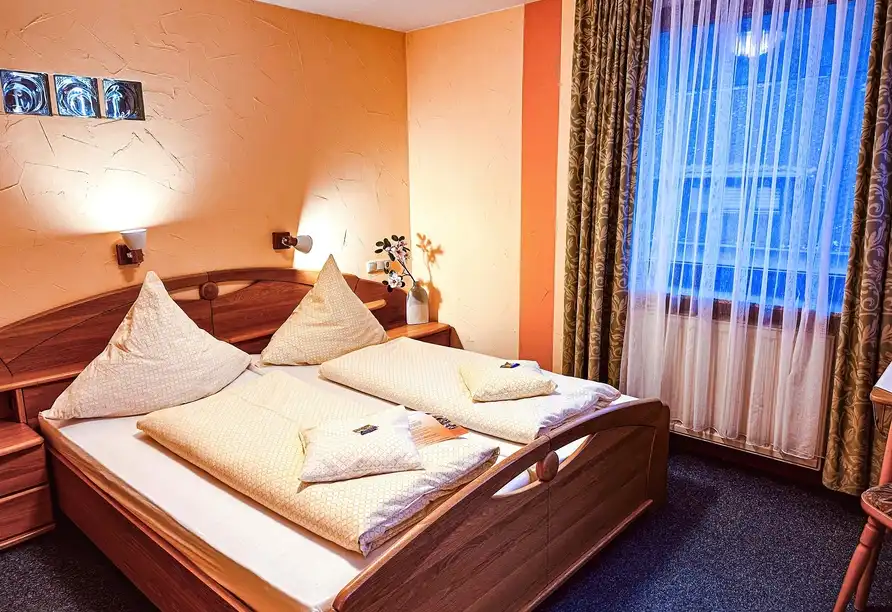 Ein Zimmer im Hotel Loreleyblick in St. Goar mit einem gemütlichen Bettenbereich, einem Fenster mit Vorhängen und einem