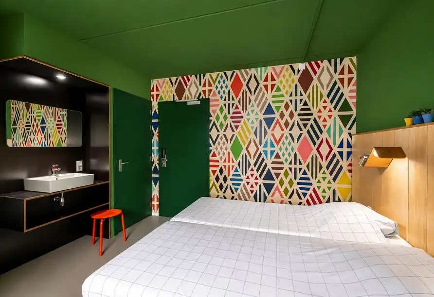 Buntes Doppelzimmer mit grafischem Wandmuster im Stayokay Hostel Dordrecht