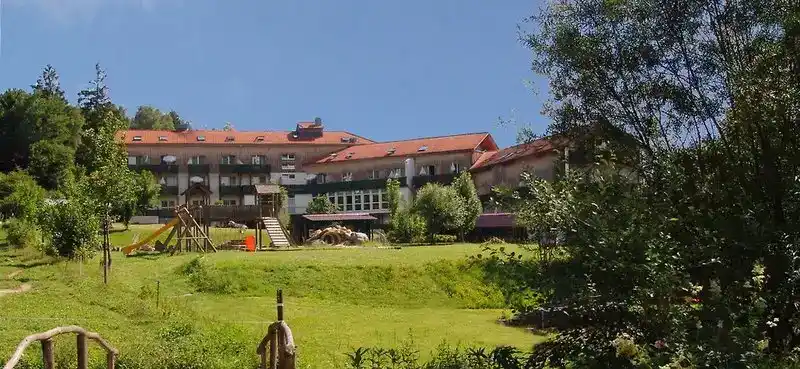 Ein großes, rustikales Sporthotel namens "Am Pfahl Viechtach" im Außenbereich. Die Gebäude haben rote Dächer und sind