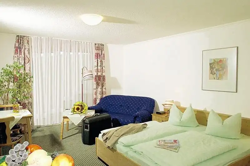 Ein Zimmer im Sporthotel Am Pfahl Viechtach. Das Zimmer ist mit einem Bett, einem Sofa und einem Balkon ausgestattet. Es