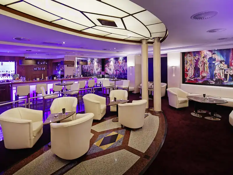 Ein luxuriöses Loungebereich im 5-Sterne Parkhotel Bremen mit weiß gekleideten Sofas und Stühlen, einem Barbereich und