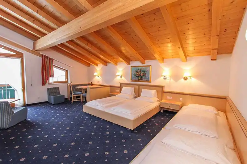 Ein Zimmer im Gasthof Bad Hochmoos mit Holzverkleidung an den Wänden und Decke. Das Zimmer verfügt über ein Bett und zwei
