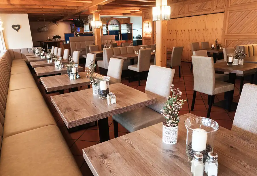 Einen gemütlichen Restaurantbereich im WAGNERS Hotel Steinwiesen. Die Tische sind mit Holenzügen und Dekorationen aus
