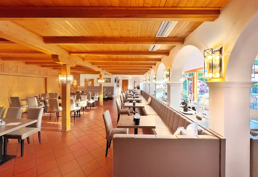 Einen gemütlichen Restaurantbereich im WAGNERS Hotel Steinwiesen. Die Holenzüge und die warme Beleuchtung erzeugen ein