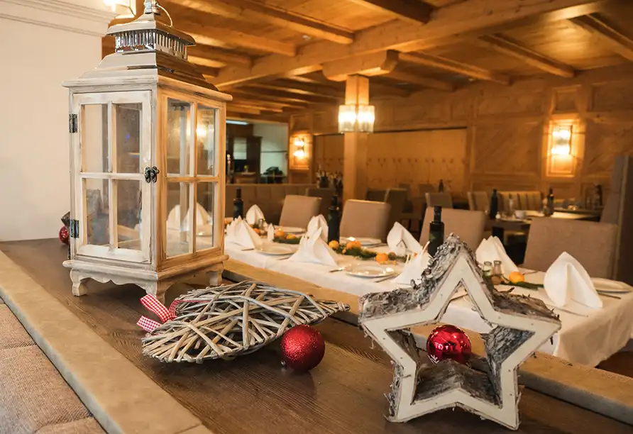 Ein festlich ausgestattetes Esszimmer im WAGNERS Hotel Steinwiesen. Die Dekoration umfasst Weihnachtsdekorationen wie eine