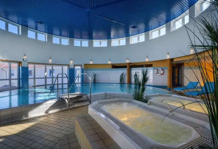 Einen Indoorpool des Hotels Wyndham Garden Wismar. Die Atmosphäre ist hell und luftig, mit einem großen Glasdach, der